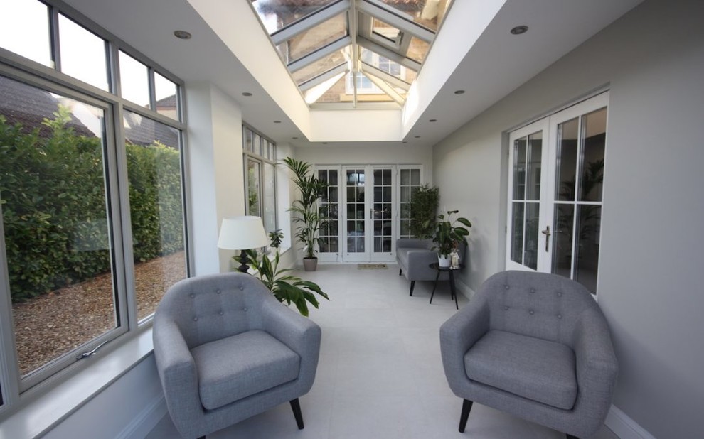 This is an example of a mid-sized contemporary sunroom in Cambridgeshire with porcelain floors, a glass ceiling and grey floor.