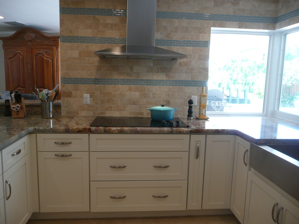 Eat-in kitchen - mid-sized transitional u-shaped porcelain tile eat-in kitchen idea in Miami with a farmhouse sink, flat-panel cabinets, white cabinets, quartzite countertops, beige backsplash, stone tile backsplash, stainless steel appliances and a peninsula