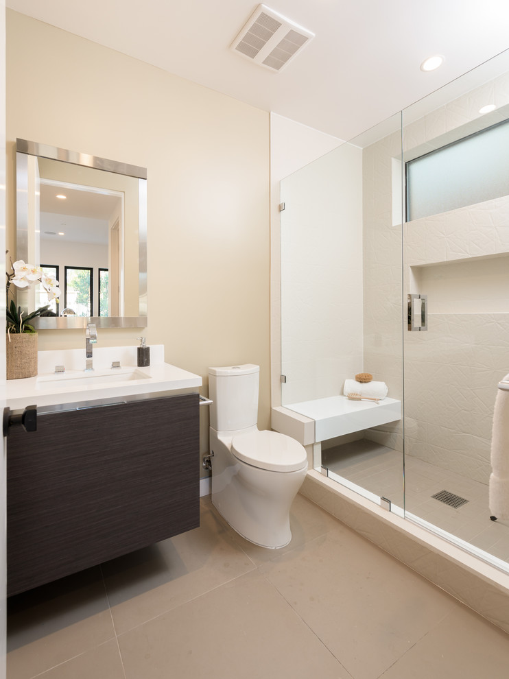 Modern master bathroom in Los Angeles with a two-piece toilet, beige tile, beige walls, concrete floors and an undermount sink.