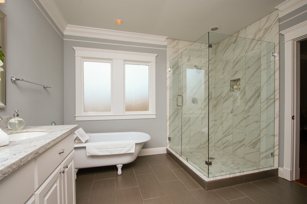 This is an example of a large traditional master bathroom in Houston with white cabinets, a claw-foot tub, a corner shower, white tile, an undermount sink, raised-panel cabinets, porcelain tile, grey walls, porcelain floors, granite benchtops and a hinged shower door.
