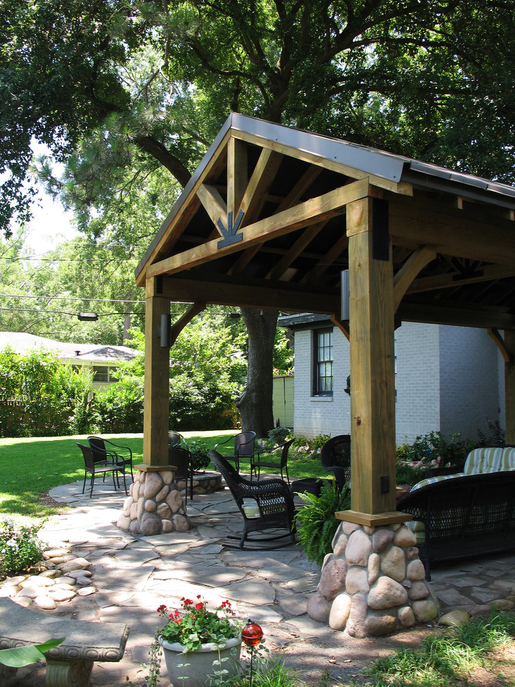 This is an example of a mid-sized arts and crafts backyard patio in New Orleans with natural stone pavers and an awning.