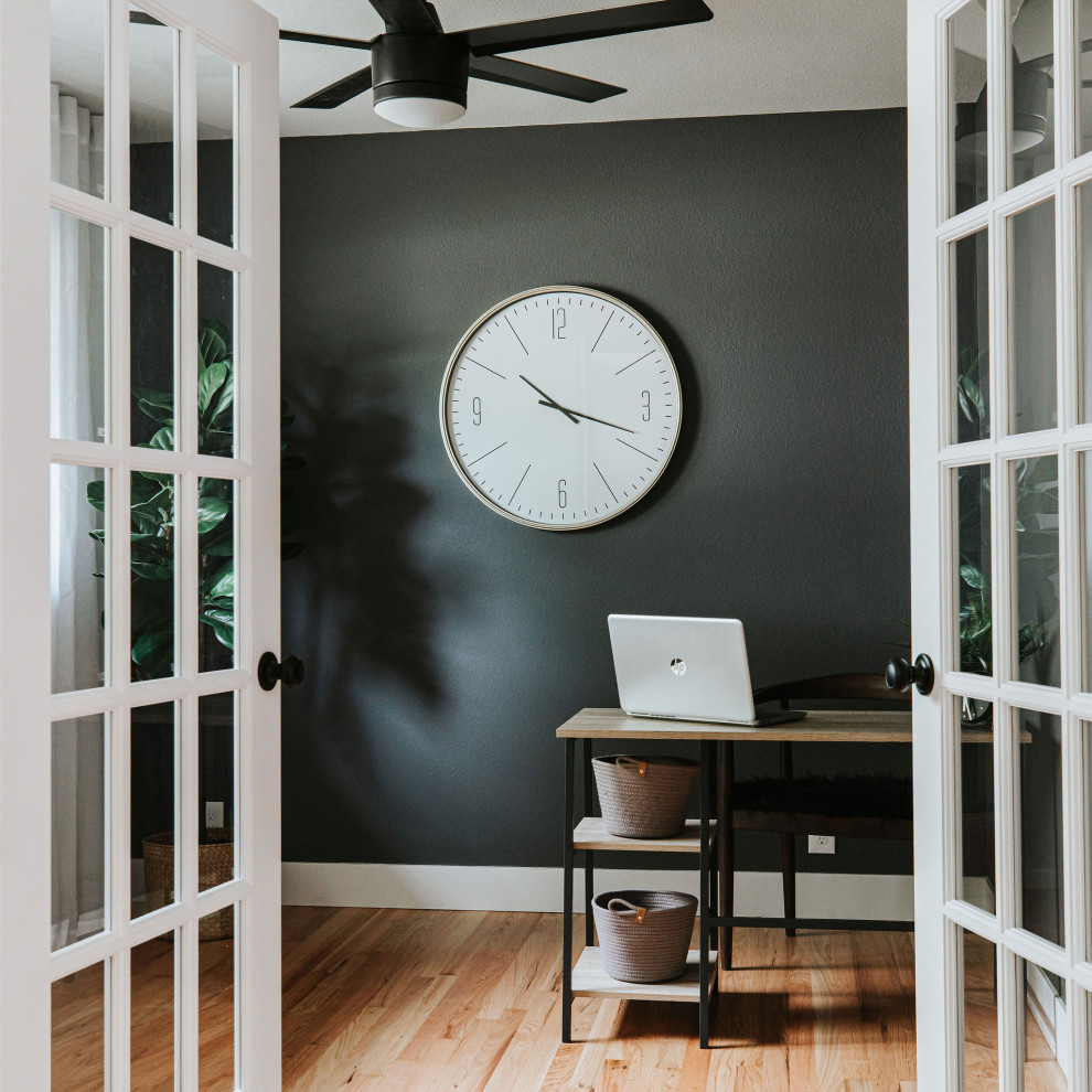 Photo of a small contemporary study room in Denver with black walls, light hardwood floors and a freestanding desk.