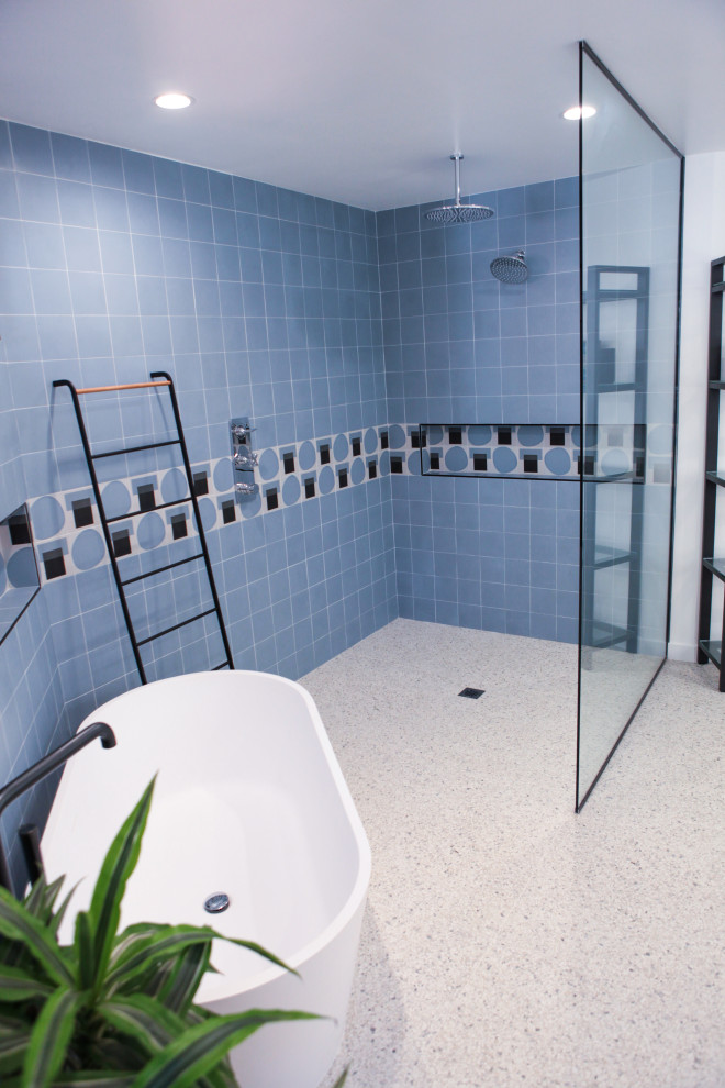 Photo of a mid-sized modern master bathroom in Los Angeles with open cabinets, brown cabinets, a freestanding tub, a curbless shower, a one-piece toilet, blue tile, subway tile, white walls, terrazzo floors, a wall-mount sink, yellow floor and an open shower.