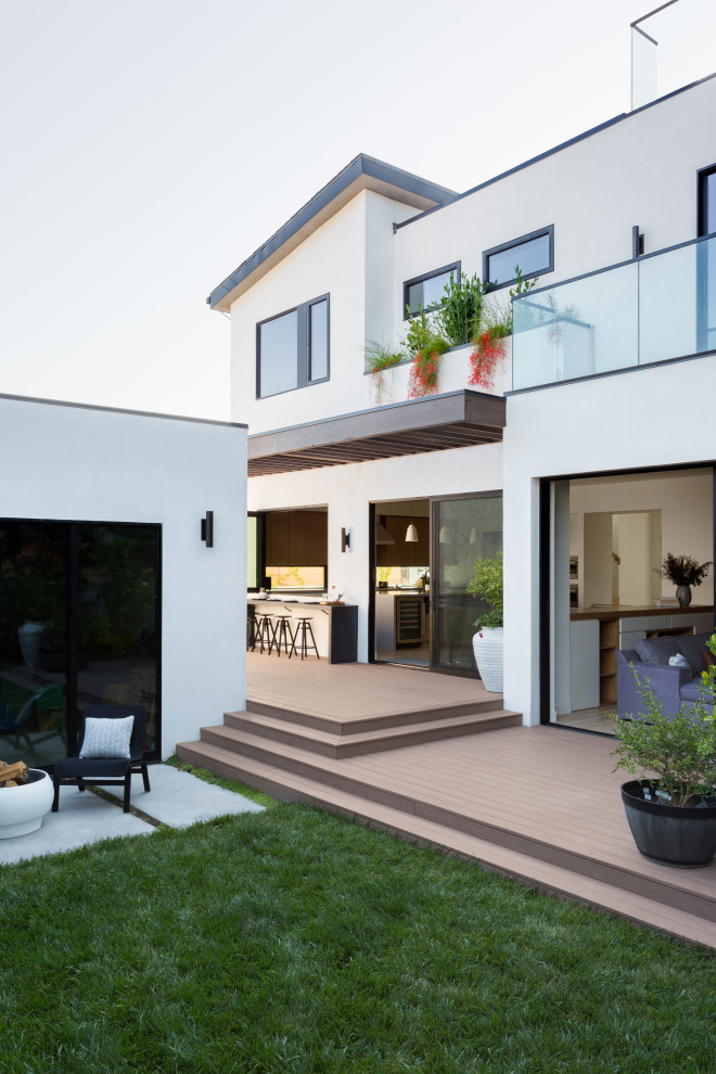 Ispirazione per una terrazza design di medie dimensioni, dietro casa e a piano terra con un focolare, una pergola e parapetto in vetro