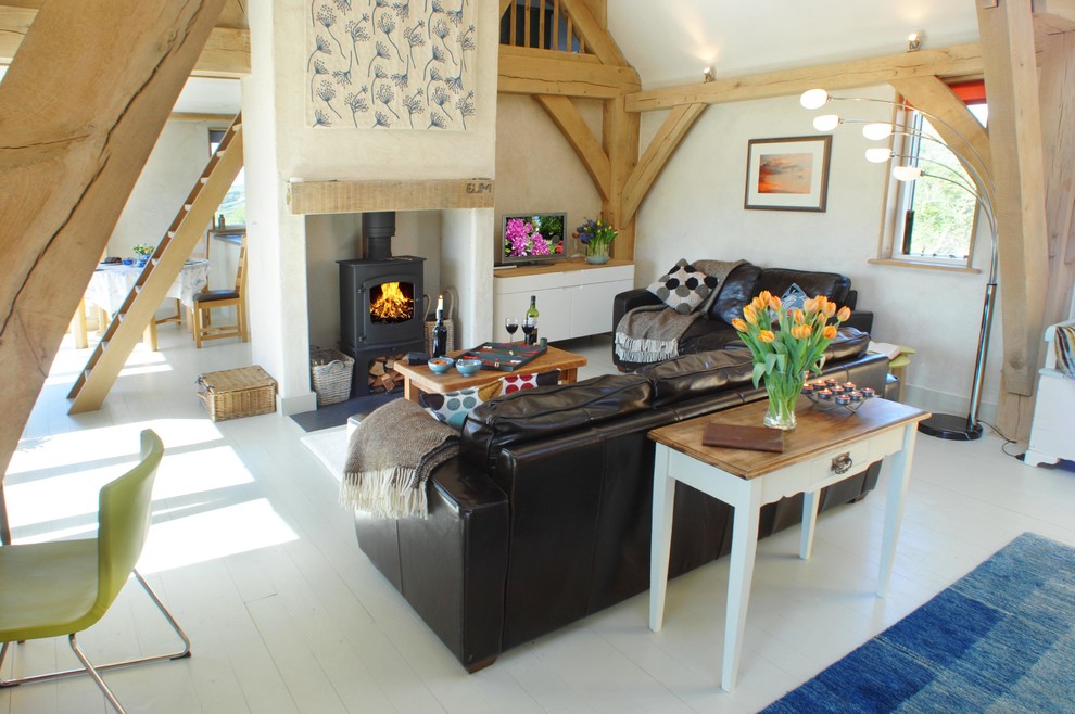 Inspiration for a country open concept living room in Devon with white walls, a wood stove and painted wood floors.