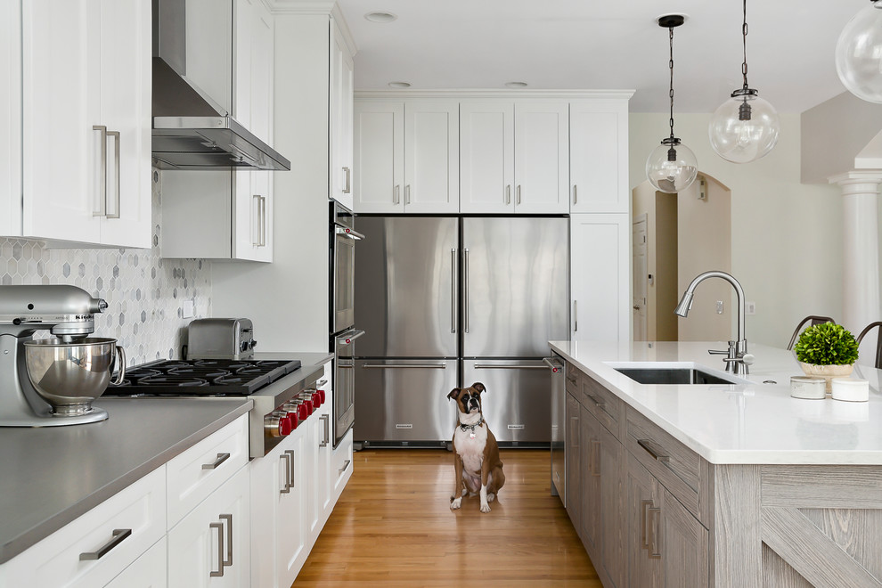 Inspiration for a large transitional light wood floor open concept kitchen remodel in Chicago with an undermount sink, shaker cabinets, white cabinets, quartz countertops, gray backsplash, marble backsplash, stainless steel appliances and an island