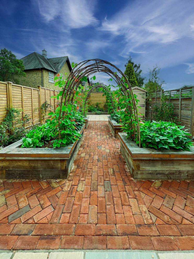 Ispirazione per un giardino tradizionale esposto in pieno sole di medie dimensioni e dietro casa in estate con pavimentazioni in mattoni e recinzione in legno