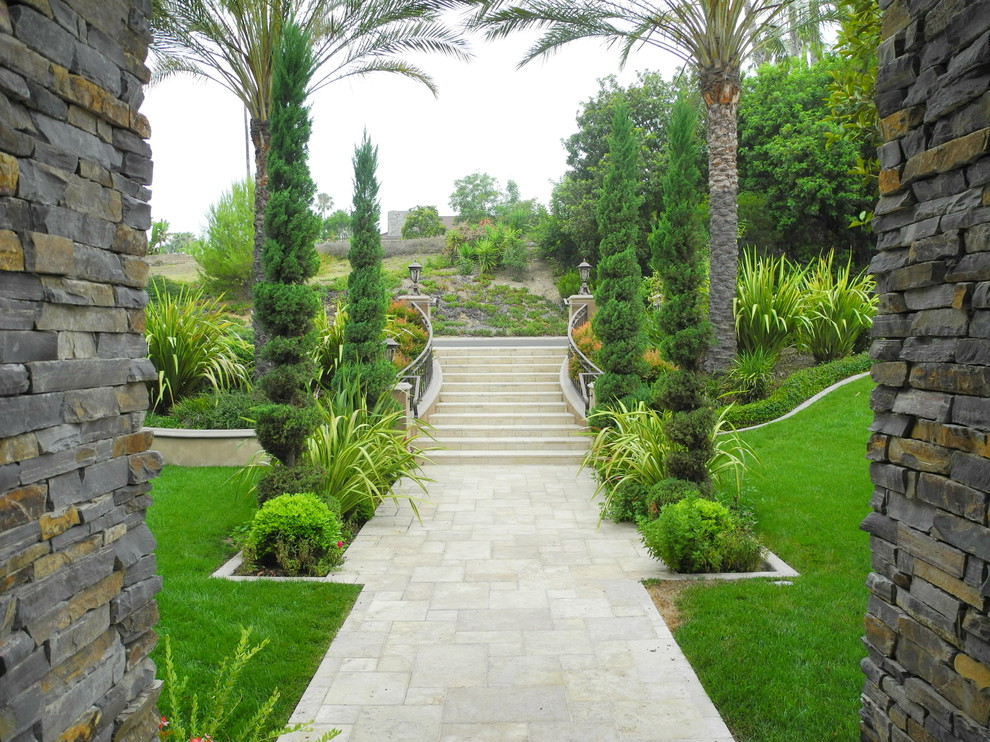 Design ideas for a mid-sized tropical full sun formal garden in Orange County with natural stone pavers.