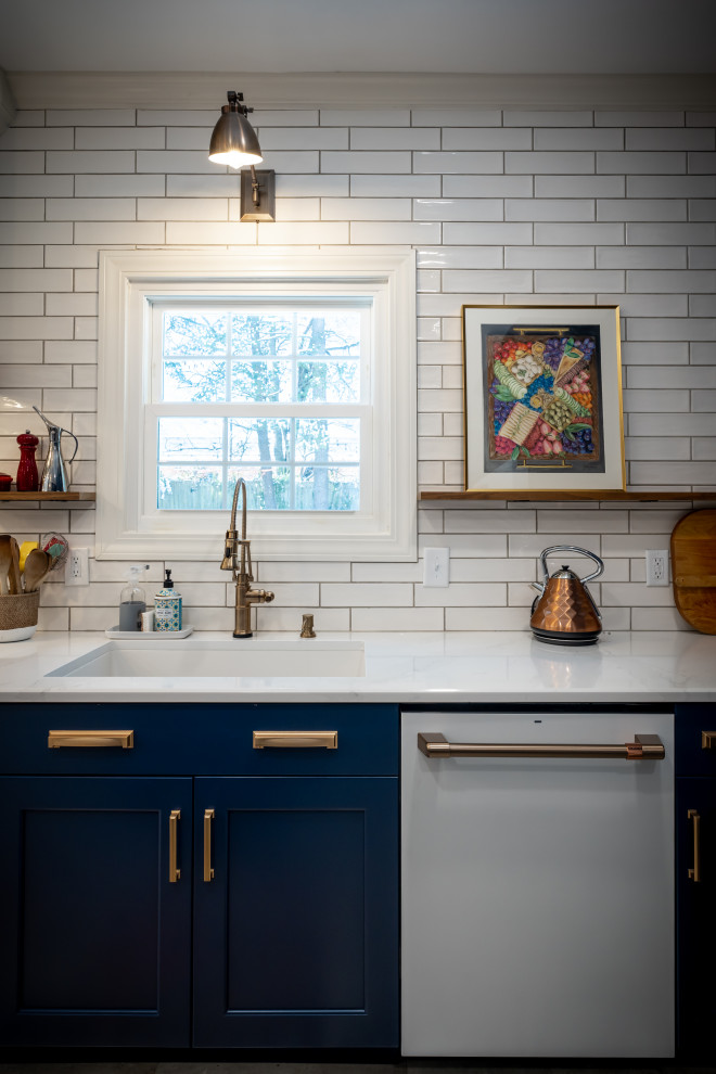 ナッシュビルにある高級な中くらいなシャビーシック調のおしゃれなキッチン (アンダーカウンターシンク、シェーカースタイル扉のキャビネット、青いキャビネット、クオーツストーンカウンター、白いキッチンパネル、セラミックタイルのキッチンパネル、白い調理設備、磁器タイルの床、ベージュの床、白いキッチンカウンター) の写真