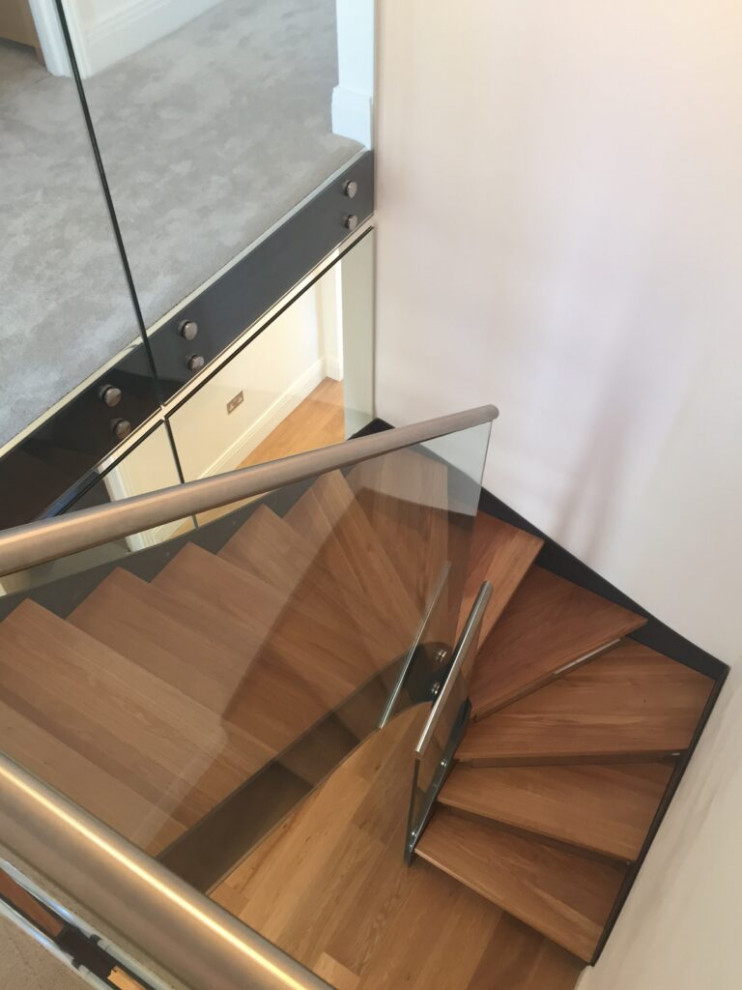 Réalisation d'un escalier minimaliste en U de taille moyenne avec des marches en bois, des contremarches en verre et un garde-corps en verre.