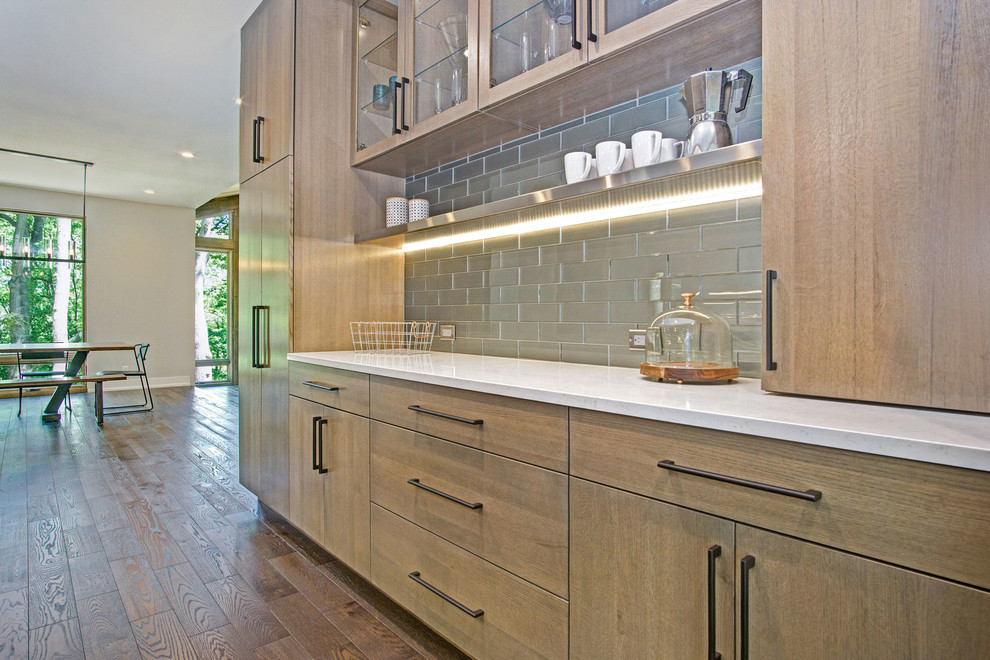 Inspiration for a rustic medium tone wood floor kitchen remodel in Grand Rapids with an undermount sink, flat-panel cabinets, quartz countertops, green backsplash, glass tile backsplash and stainless steel appliances