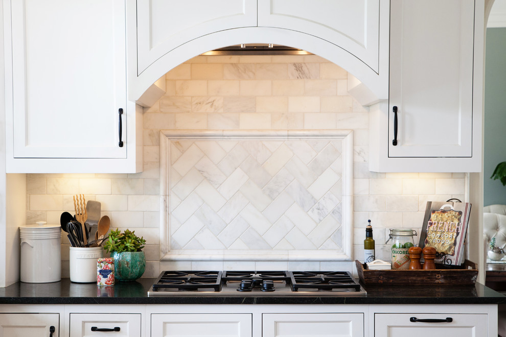 This is an example of a mid-sized traditional u-shaped kitchen in San Diego with recessed-panel cabinets, white cabinets, soapstone benchtops, white splashback, stone tile splashback and with island.