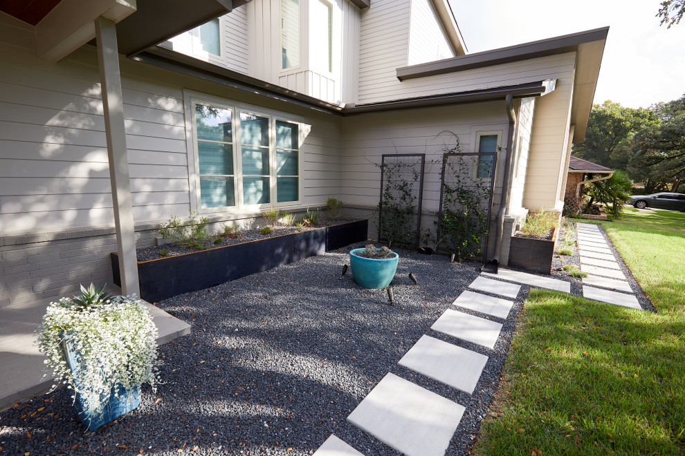 Design ideas for a large contemporary front driveway partial sun garden for summer in Austin with a retaining wall, concrete paving and a metal fence.
