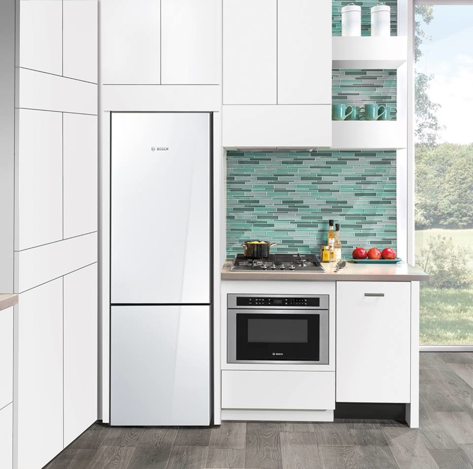 Photo of a small modern l-shaped separate kitchen in Houston with flat-panel cabinets, white cabinets, solid surface benchtops, green splashback, glass tile splashback, white appliances and plywood floors.