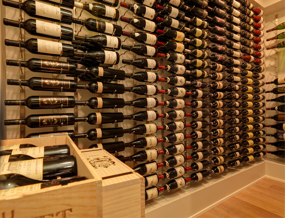 Mid-sized modern wine cellar in Vancouver with display racks, light hardwood floors and brown floor.