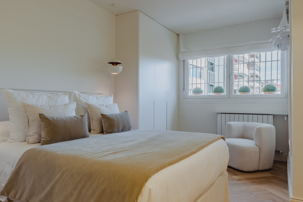 Imagen de dormitorio principal y beige y blanco clásico renovado de tamaño medio con paredes blancas, suelo de madera clara, suelo beige, bandeja y boiserie