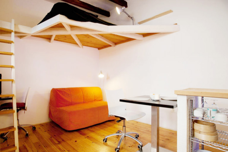Imagen de sala de estar tipo loft mediterránea pequeña con paredes blancas, suelo de madera en tonos medios y vigas vistas