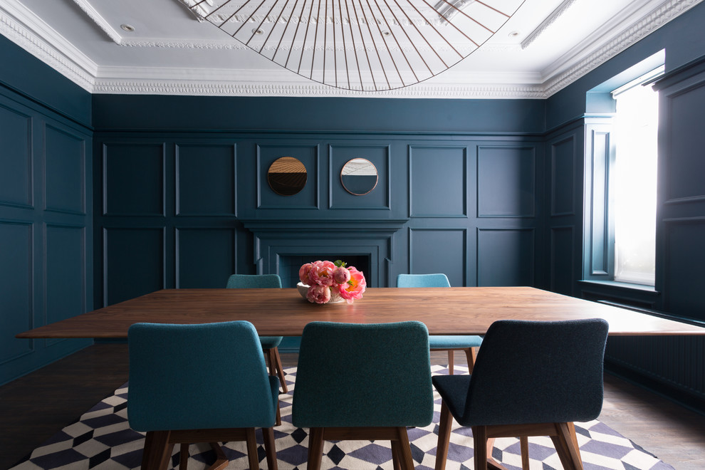 Inspiration for a midcentury separate dining room in London with blue walls, dark hardwood floors, a standard fireplace and a plaster fireplace surround.