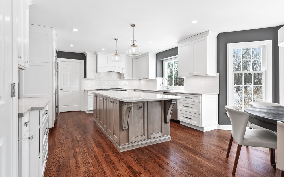 Eat-in kitchen - large transitional u-shaped medium tone wood floor and brown floor eat-in kitchen idea in Chicago with a single-bowl sink, shaker cabinets, white cabinets, quartzite countertops, white backsplash, porcelain backsplash, stainless steel appliances, an island and gray countertops