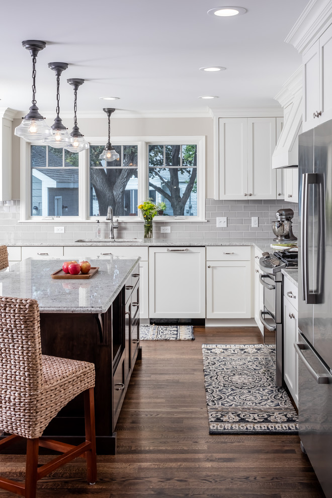 Mid-sized traditional l-shaped eat-in kitchen in Minneapolis with shaker cabinets, white cabinets, granite benchtops, grey splashback, subway tile splashback, stainless steel appliances, dark hardwood floors and with island.