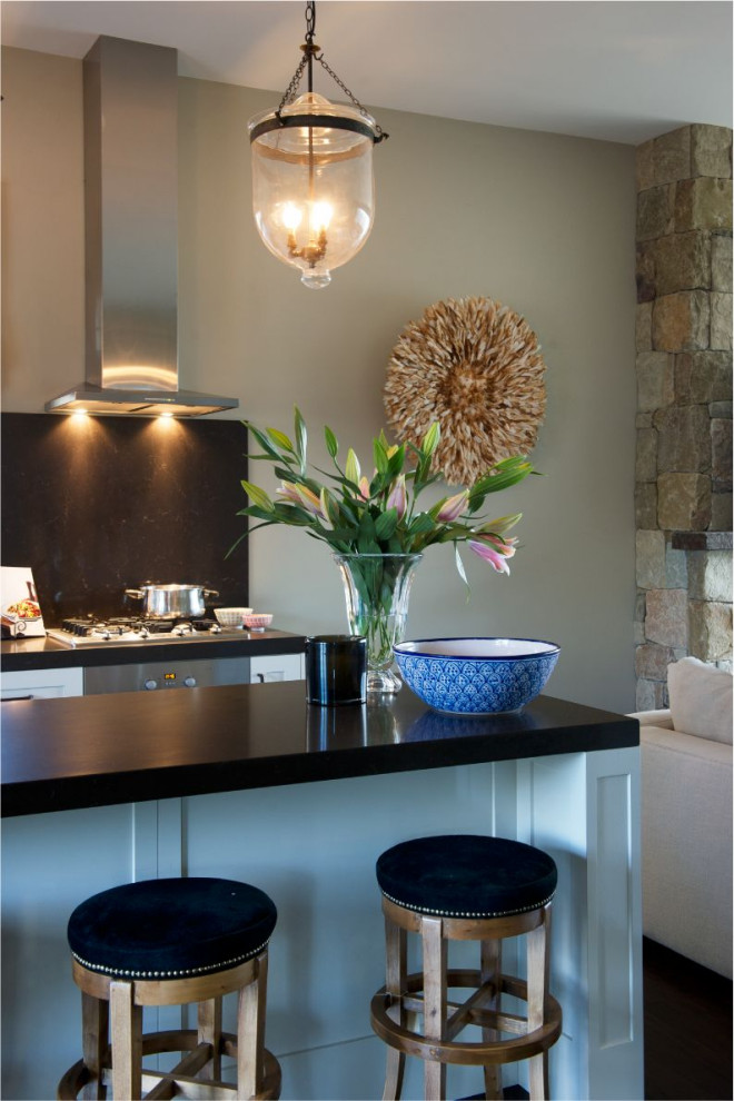 Mid-sized country single-wall open plan kitchen in Central Coast with a drop-in sink, solid surface benchtops, black splashback, stone slab splashback, stainless steel appliances, dark hardwood floors, with island, brown floor and black benchtop.