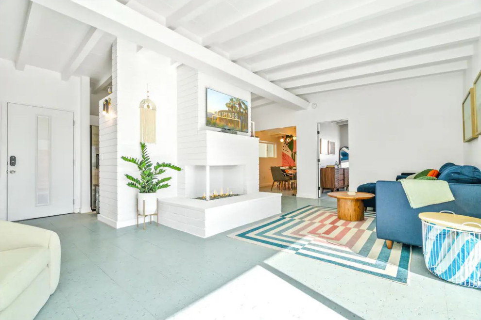 Exempel på ett 50 tals vardagsrum, med vita väggar, laminatgolv, en standard öppen spis, en spiselkrans i tegelsten, en väggmonterad TV och blått golv