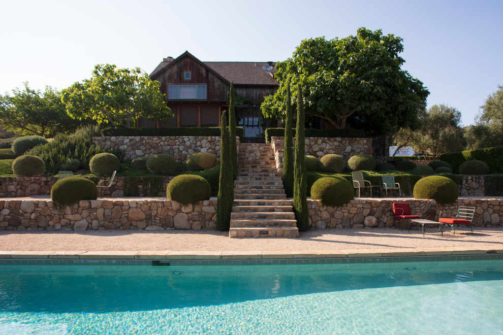Diseño de piscina alargada campestre en patio trasero con paisajismo de piscina