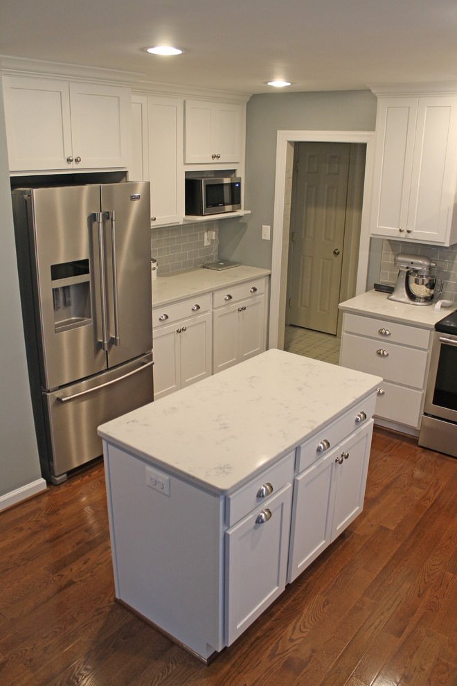Inspiration for a mid-sized transitional u-shaped eat-in kitchen in Baltimore with an undermount sink, shaker cabinets, white cabinets, granite benchtops, grey splashback, subway tile splashback, stainless steel appliances, medium hardwood floors, with island, brown floor and white benchtop.