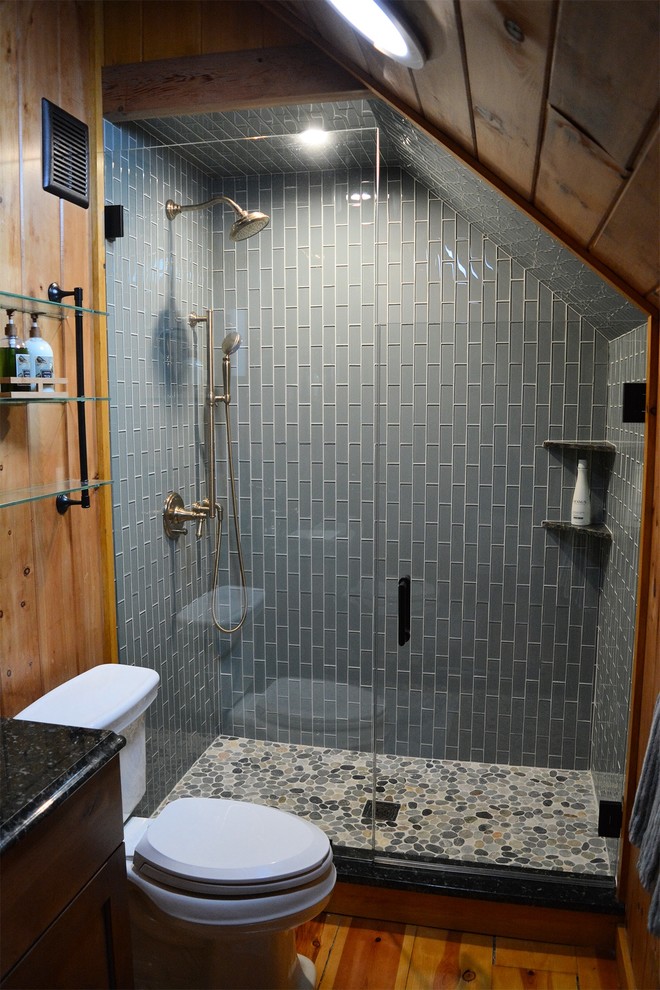 Country bathroom in New York with shaker cabinets, medium wood cabinets, an alcove shower, a two-piece toilet, glass tile, granite benchtops and a hinged shower door.