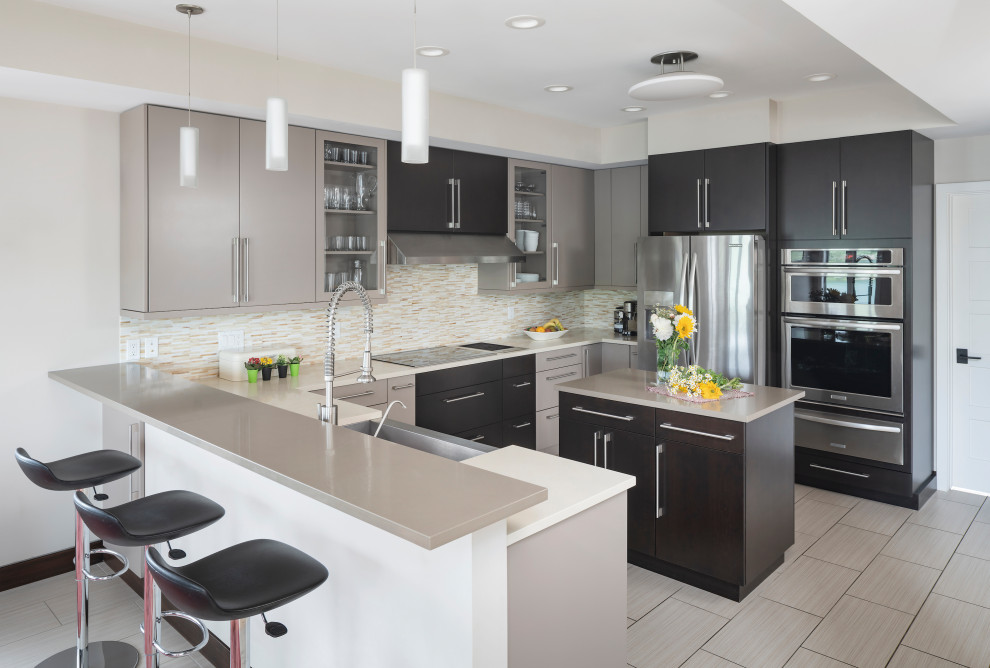This is an example of a mid-sized contemporary u-shaped open plan kitchen in Detroit with a farmhouse sink, flat-panel cabinets, beige cabinets, quartz benchtops, beige splashback, glass tile splashback, stainless steel appliances, porcelain floors, with island, beige floor, beige benchtop and recessed.