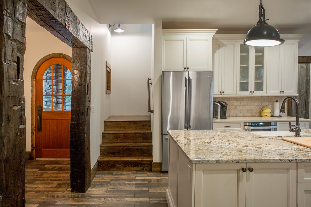 Open concept kitchen - mid-sized medium tone wood floor open concept kitchen idea with white cabinets, granite countertops, stainless steel appliances and an island