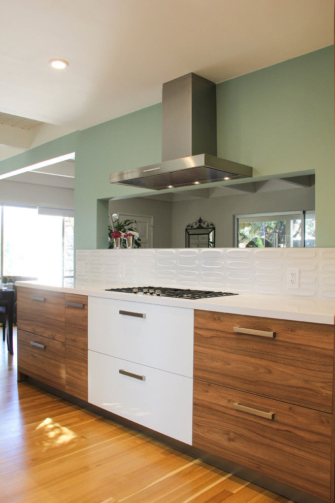 Mid-sized contemporary u-shaped eat-in kitchen in Los Angeles with a drop-in sink, flat-panel cabinets, white cabinets, quartz benchtops, white splashback, porcelain splashback, stainless steel appliances and no island.