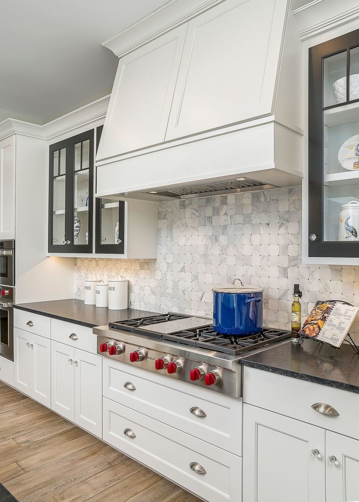 This is an example of a mid-sized beach style l-shaped eat-in kitchen in Chicago with shaker cabinets, white cabinets, soapstone benchtops, grey splashback, marble splashback, stainless steel appliances, dark hardwood floors, with island and beige floor.