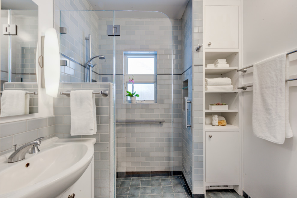 Bild på ett litet vintage vit vitt badrum, med släta luckor, vita skåp, en kantlös dusch, en vägghängd toalettstol, blå kakel, keramikplattor, vita väggar, klinkergolv i porslin, ett integrerad handfat, bänkskiva i akrylsten, blått golv och med dusch som är öppen