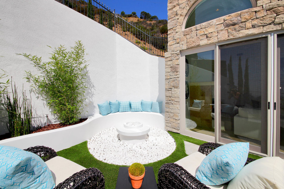 Large mediterranean front yard full sun xeriscape in Los Angeles with a fire feature and river rock.