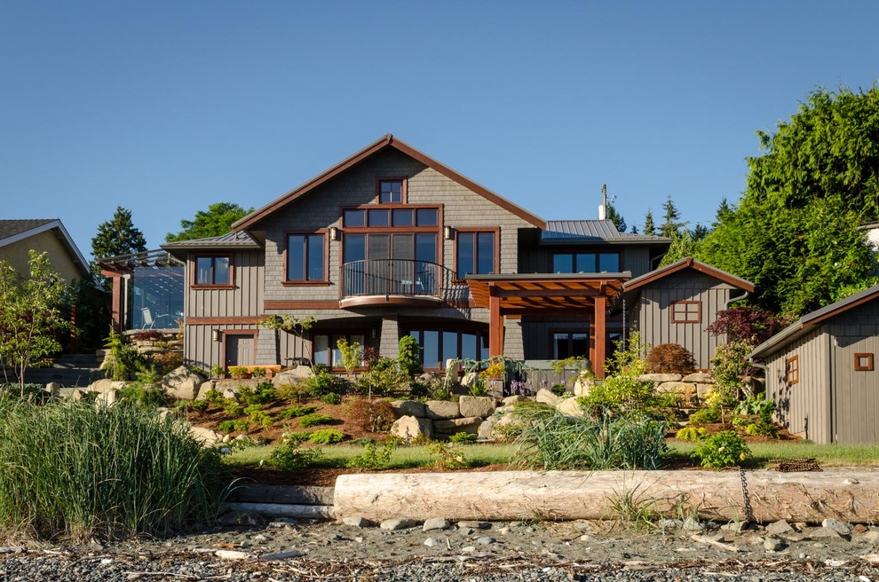 Large arts and crafts two-storey brown exterior in Vancouver with wood siding and a gable roof.