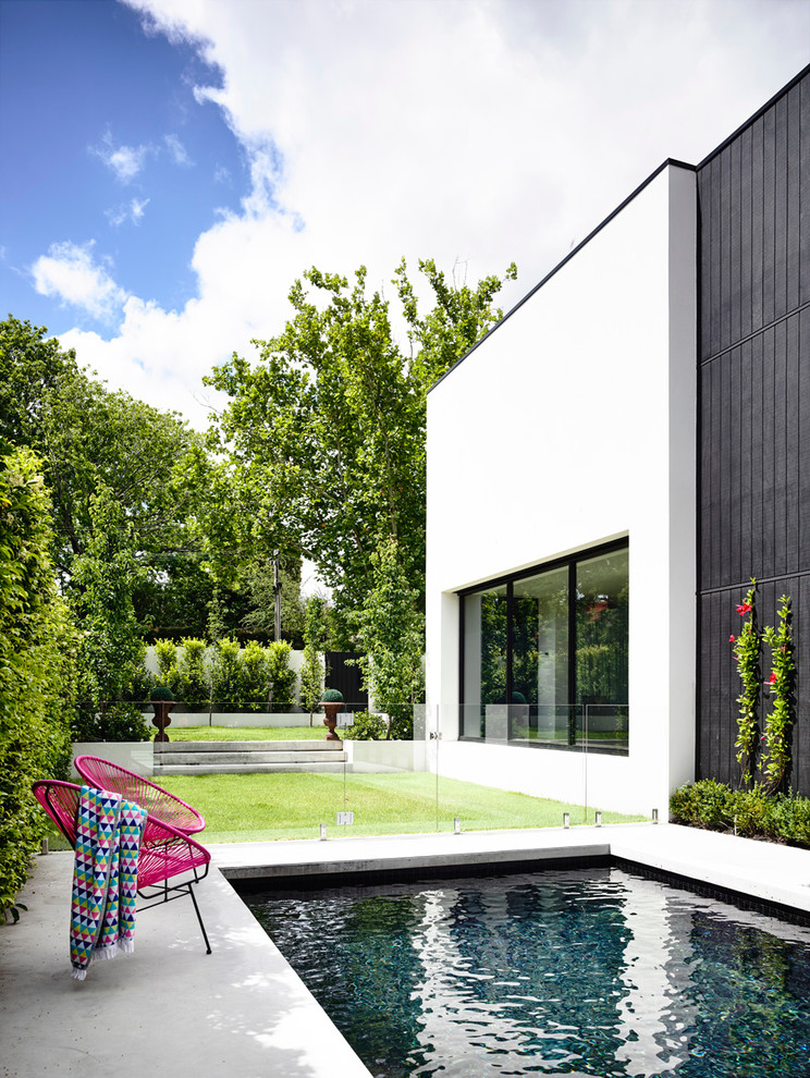 Backyard rectangular lap pool in Melbourne with a hot tub and concrete slab.