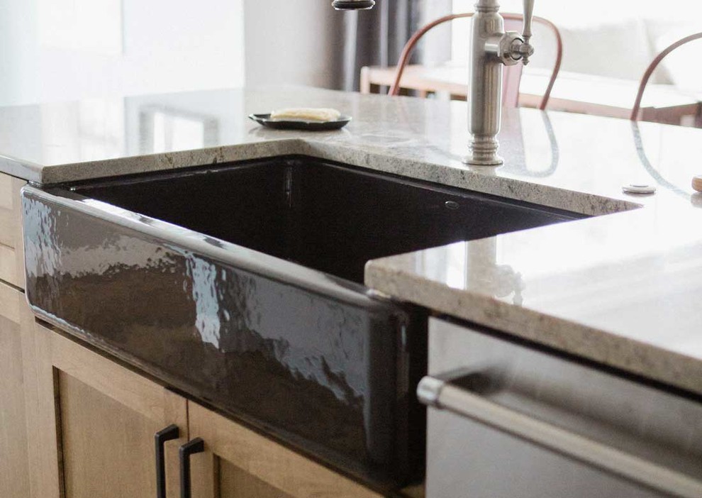 Example of a mid-sized transitional kitchen design with a farmhouse sink, granite countertops, gray backsplash, stainless steel appliances and an island