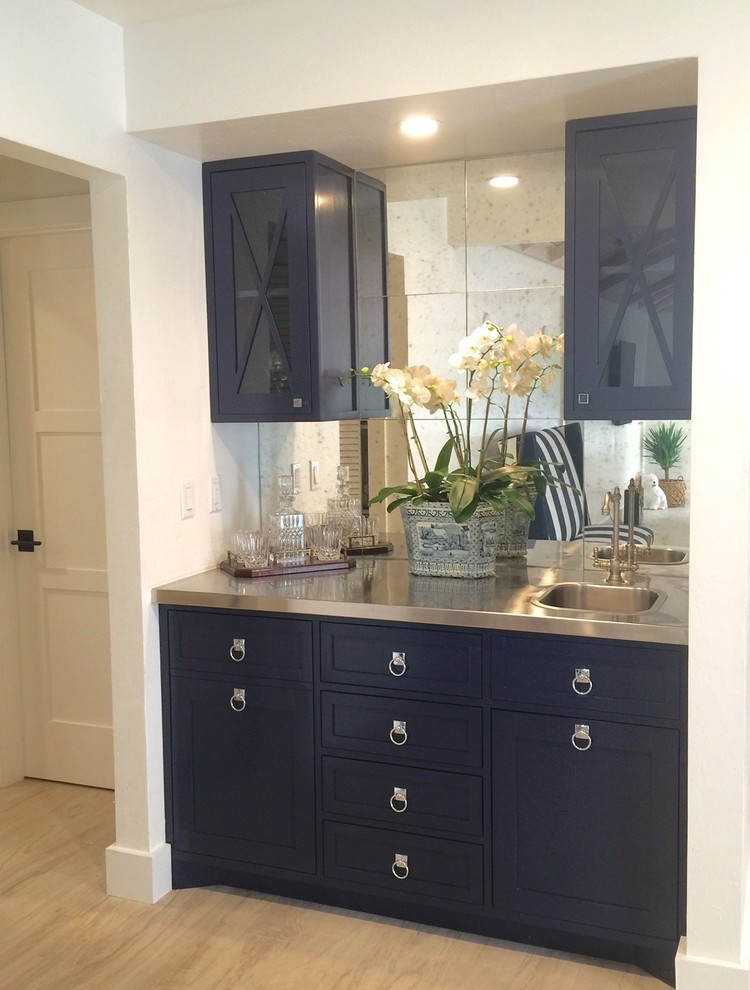 Photo of a beach style wet bar in Montreal with blue cabinets, stainless steel benchtops, mirror splashback and ceramic floors.