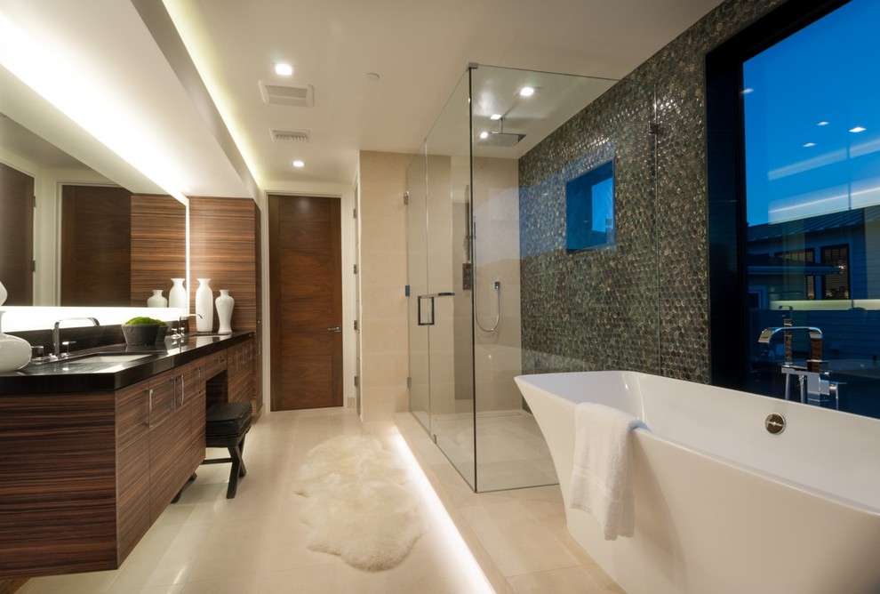 Inspiration for a large modern master bathroom in Los Angeles with flat-panel cabinets, dark wood cabinets, a freestanding tub, a double shower, a one-piece toilet, green tile, beige walls, an undermount sink and porcelain floors.