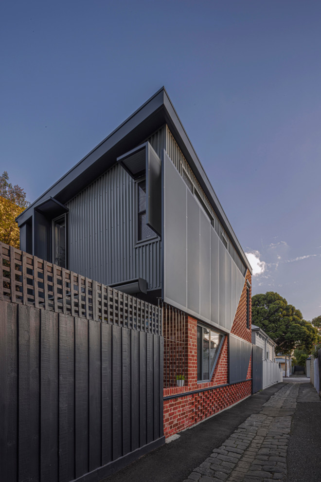 Mittelgroßes, Zweistöckiges Modernes Einfamilienhaus mit Backsteinfassade, roter Fassadenfarbe, Blechdach und grauem Dach in Melbourne