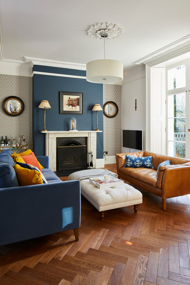 Design ideas for a traditional formal living room in London with multi-coloured walls, medium hardwood floors, a standard fireplace and brown floor.