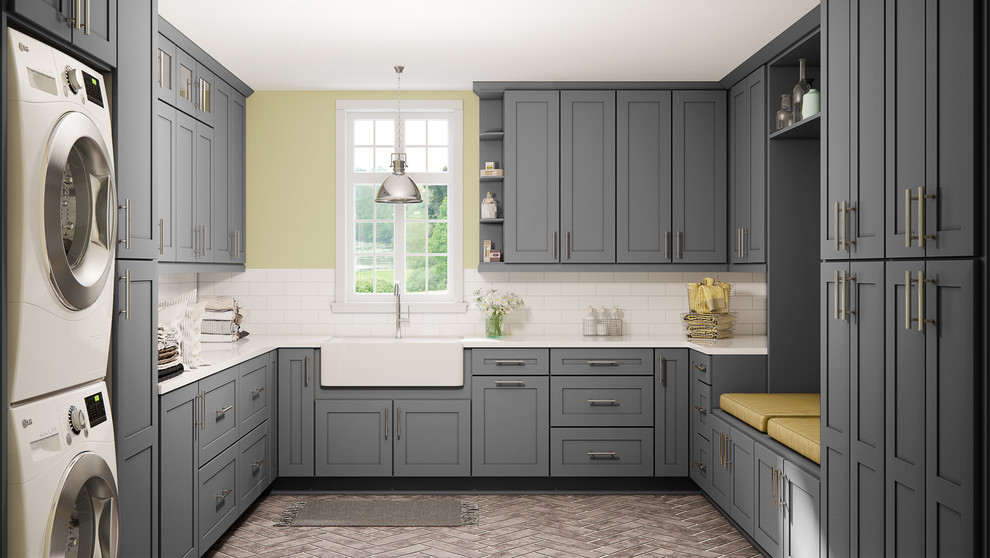 Inspiration for a large modern u-shaped dedicated laundry room with a farmhouse sink, shaker cabinets, grey cabinets, marble benchtops, yellow walls, porcelain floors, a stacked washer and dryer, beige floor and white benchtop.