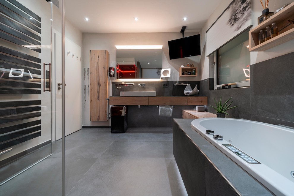 Sauna With hellen Holzschränken, Whirlpool, bodengleicher Dusche, Wandtoilette mit Spülkasten, grauen Fliesen, Steinfliesen, weißer Wandfarbe, Keramikboden, Sauna, Aufsatzwaschbecken, grauem Boden, Falttür-Duschabtrennung and brauner Waschtischplatte in Stuttgart