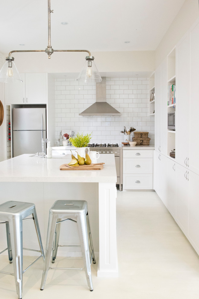 Photo of a country galley kitchen in Sydney with white cabinets, white splashback, subway tile splashback, stainless steel appliances and with island.