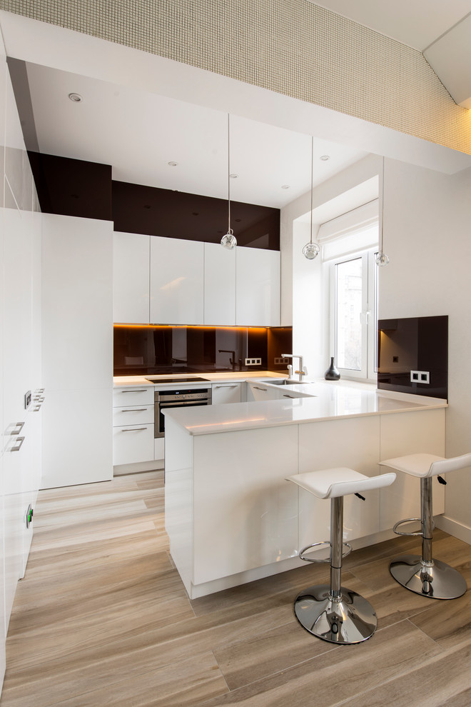 Design ideas for a small modern u-shaped open plan kitchen in Palma de Mallorca with flat-panel cabinets, white cabinets, black splashback, medium hardwood floors and a peninsula.