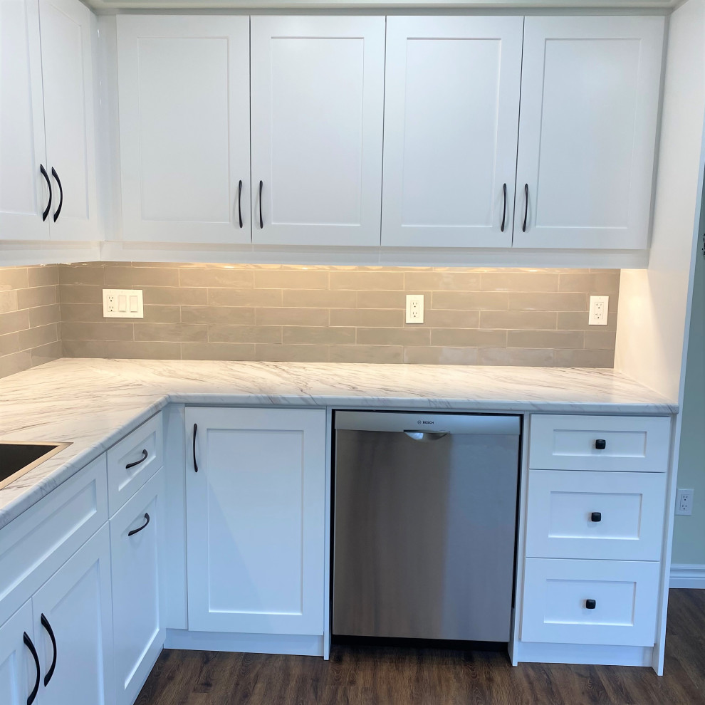Eat-in kitchen - mid-sized transitional galley vinyl floor eat-in kitchen idea in Toronto with a drop-in sink, shaker cabinets, white cabinets, laminate countertops, gray backsplash and stainless steel appliances