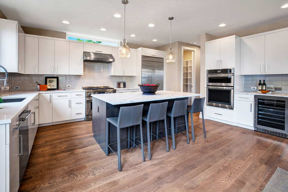 Contemporary kitchen in Seattle with an undermount sink, flat-panel cabinets, white cabinets, quartzite benchtops, stainless steel appliances, medium hardwood floors, with island, white benchtop and grey splashback.