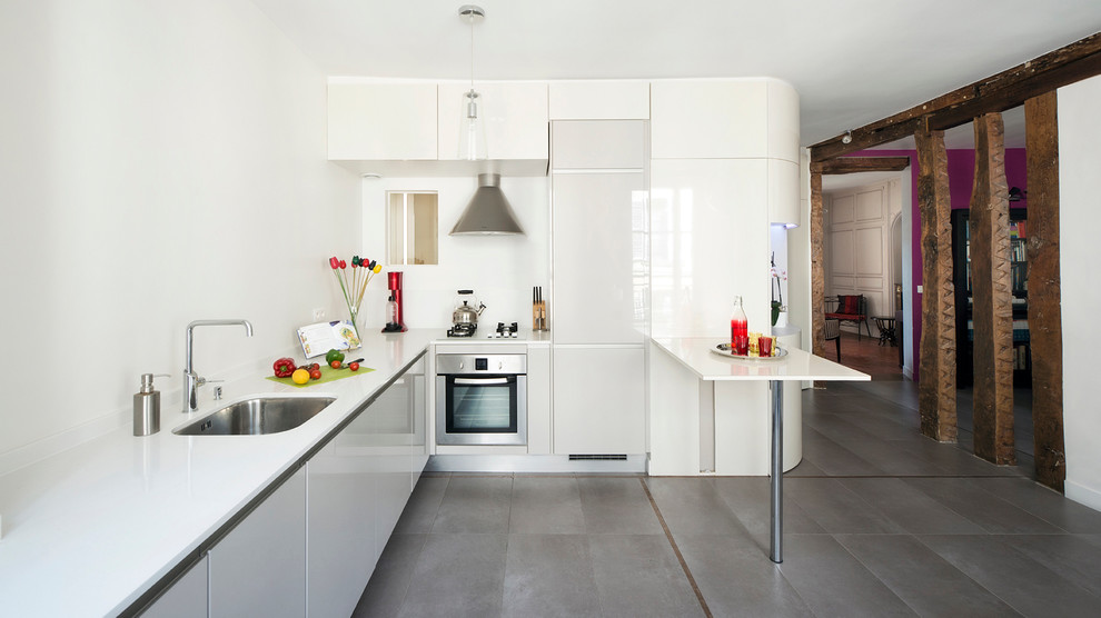 This is an example of a mid-sized contemporary l-shaped open plan kitchen in Paris with a peninsula, an undermount sink, white cabinets and grey floor.