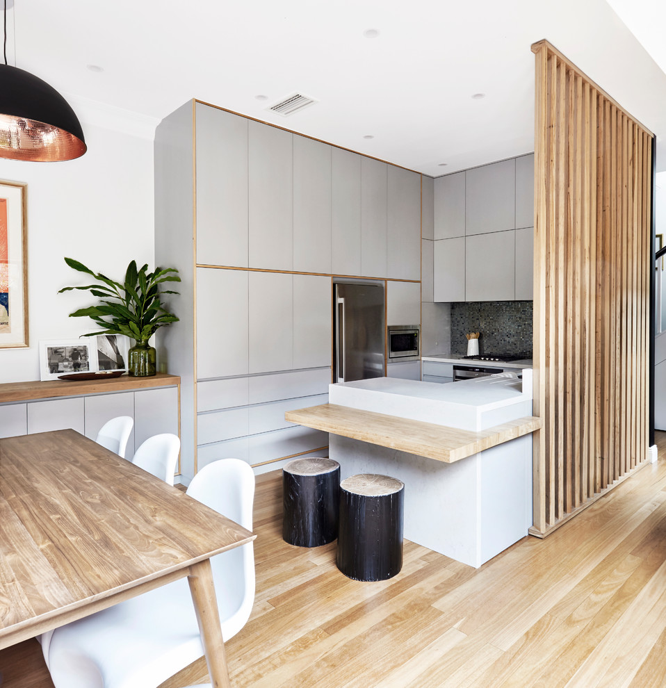 Design ideas for a mid-sized contemporary u-shaped kitchen in Melbourne with an undermount sink, recessed-panel cabinets, blue cabinets, quartz benchtops, blue splashback, mosaic tile splashback, stainless steel appliances and light hardwood floors.